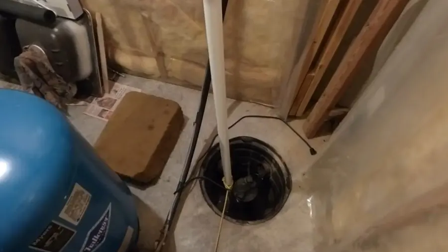 Sump pump basin, discharge pipe, and pump components during a plumbing service visit in La Crescenta